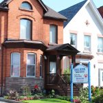 Front exterior of Excel Dental office in Hamilton, Ontario, with building entrance and roadside sign.