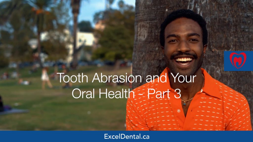 Smiling man standing by a tree in a park with overlaid text about tooth abrasion and oral health part 3.