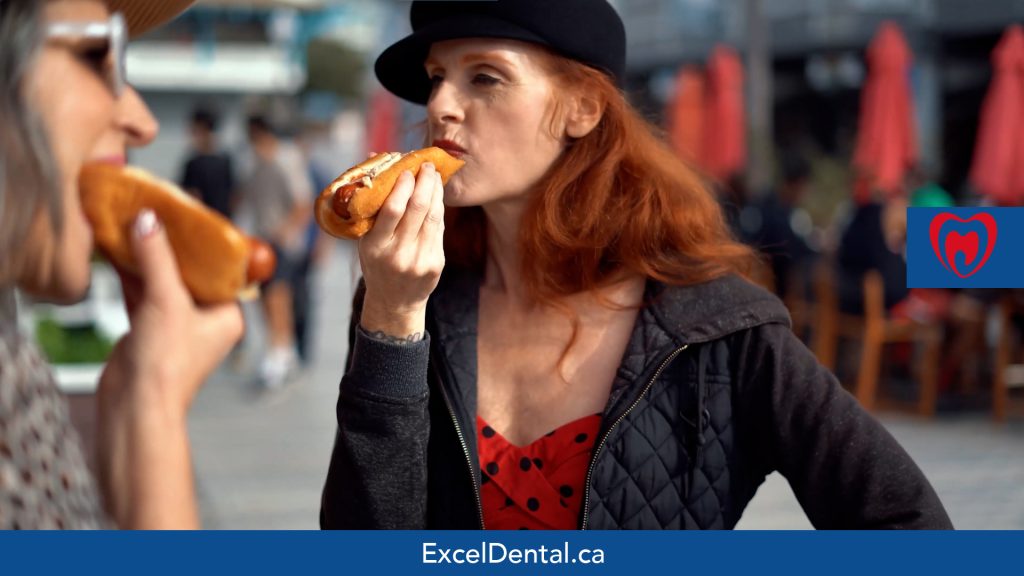 Two women eating hot dogs at an outdoor street market