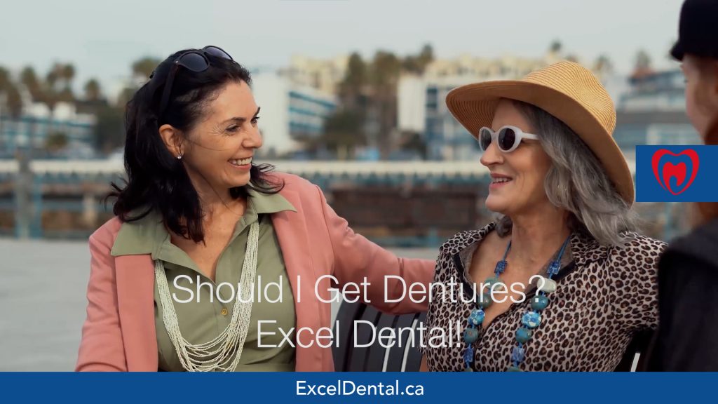 Two older women smiling together on an outdoor bench in an Excel Dental dentures promotional image.