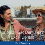Two older women smiling together on an outdoor bench in an Excel Dental dentures promotional image.