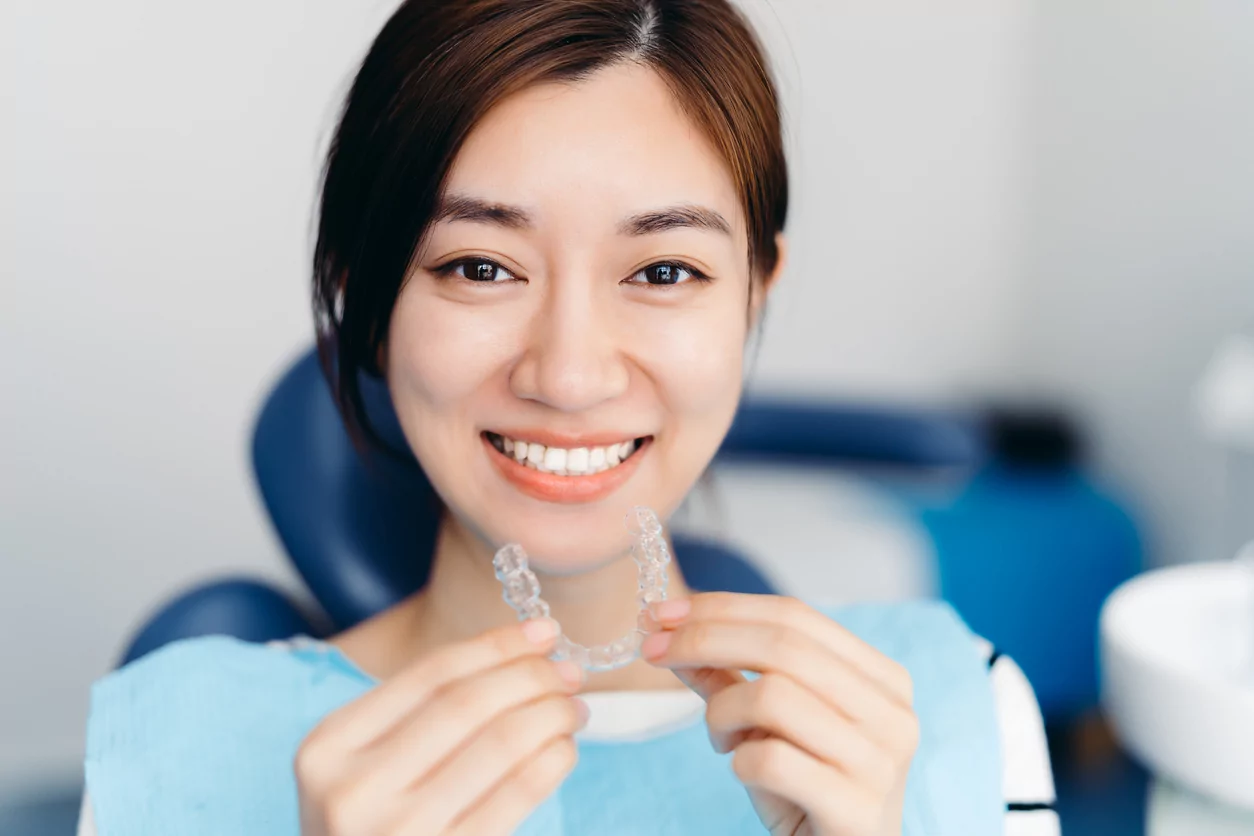 A happy teenage girl confidently showcasing her Invisalign clear aligners.