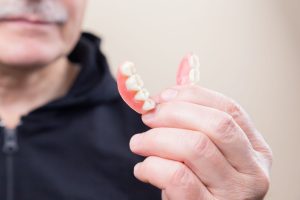 Older adult holding partial dentures in hand