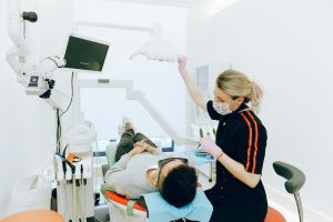 Dental professional adjusts exam light while a patient reclines in a treatment chair