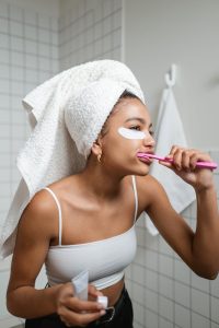 Woman brushing her teeth with a pink toothbrush in a bathroom