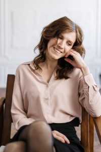 Smiling woman seated in a wooden chair indoors