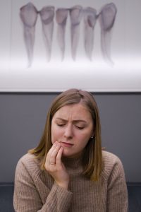 Woman holding her cheek with a pained expression beneath a framed tooth illustration