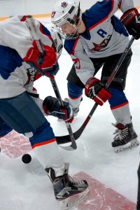 Two youth hockey players battle for the puck on the ice