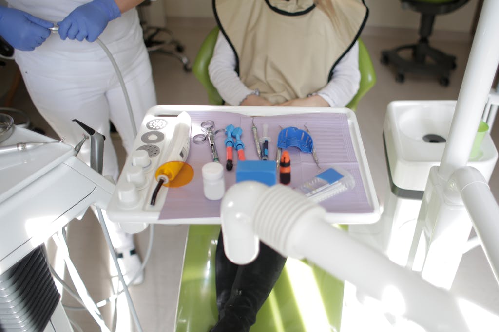 Dental operatory with a patient in the chair, clinician nearby, and instruments arranged on a tray.