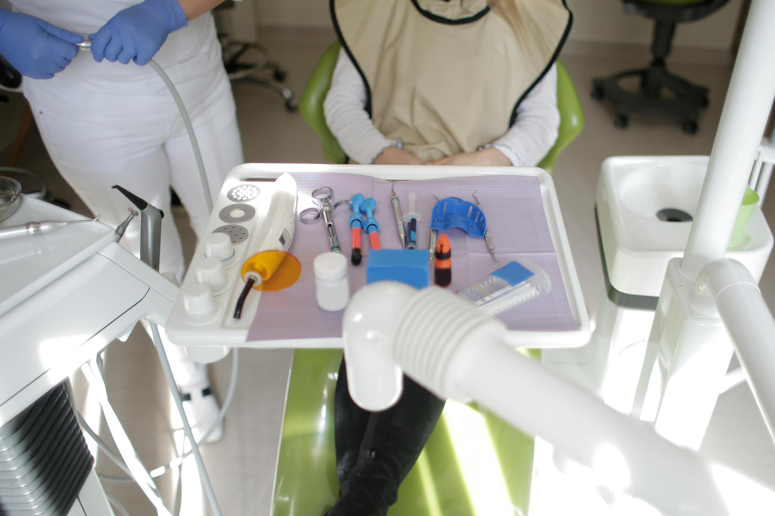 Dental operatory with a patient in the chair, clinician nearby, and instruments arranged on a tray.