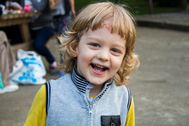 Smiling blonde child outdoors facing the camera.