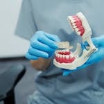 Dental professional holding a teeth model and clear tray during a clinic demonstration.