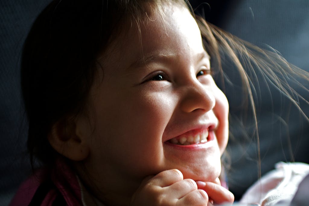 Smiling young girl with her hands under her chin indoors.