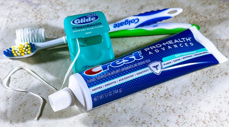 Close-up of dental care items including toothbrush, floss, and toothpaste for oral hygiene.