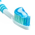 Close-up of a toothbrush head with blue toothpaste on the bristles.
