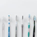 Seven toothbrushes lined up against a white background with copy space above.