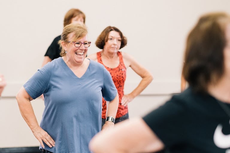 Smiling older women taking part in an indoor fitness class.