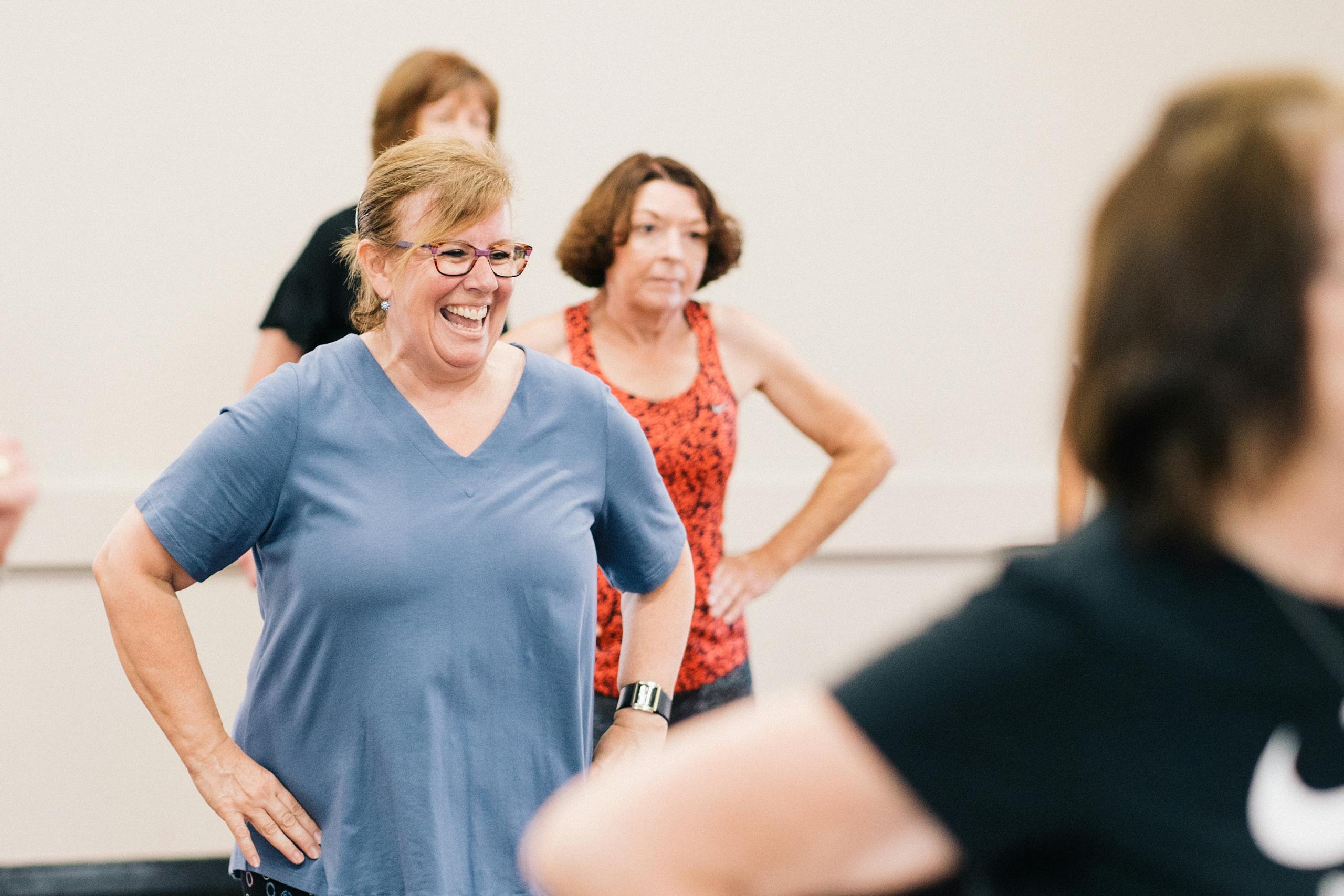 Smiling older women taking part in an indoor fitness class.