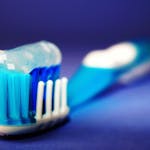 Close-up of a toothbrush head with blue bristles and toothpaste.