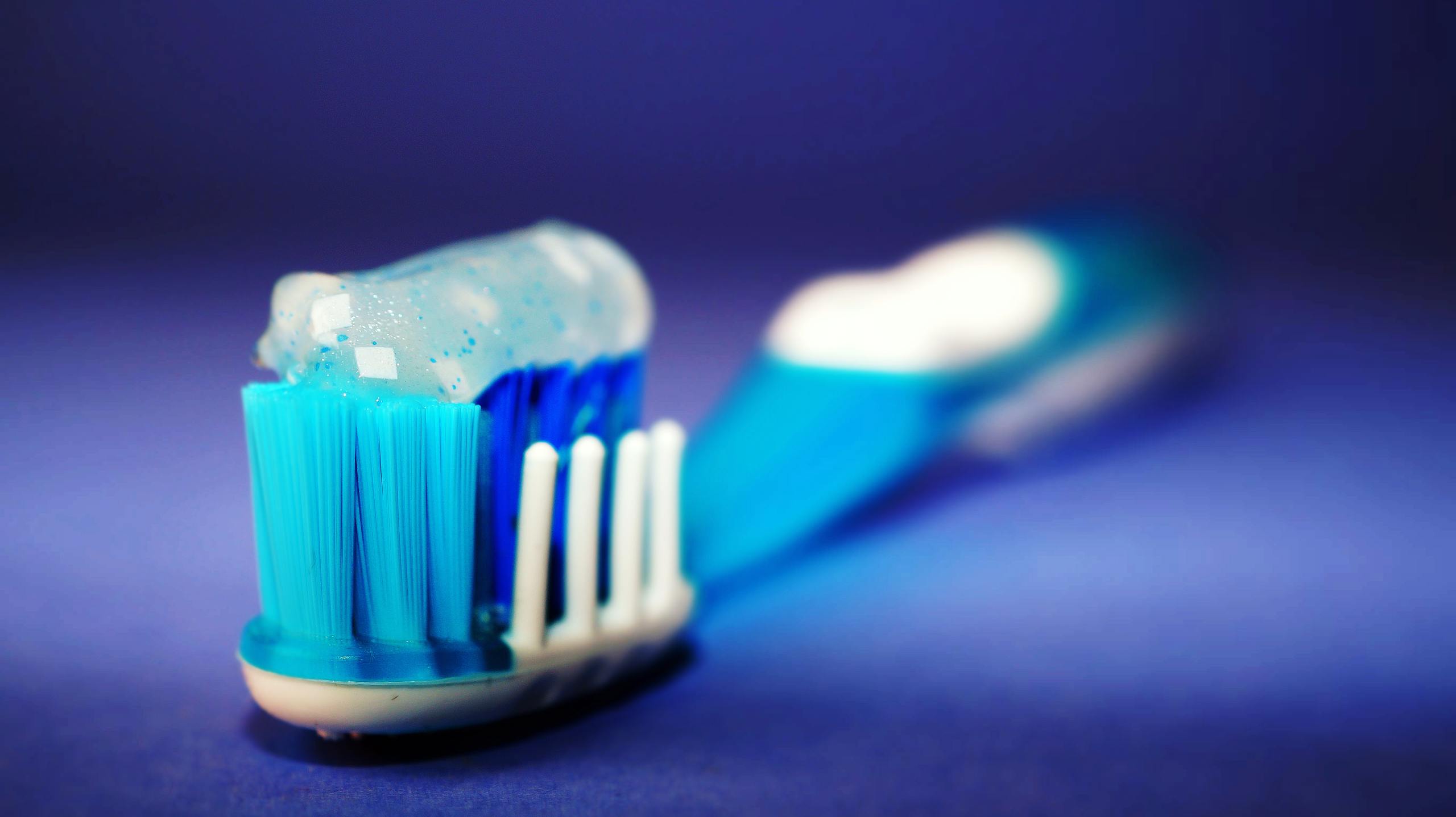 Close-up of a toothbrush head with blue bristles and toothpaste.