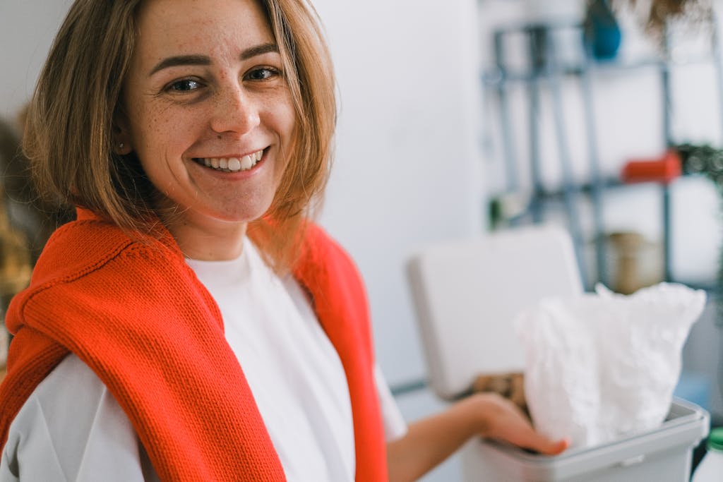 Smiling young woman indoors beside a white bin.