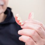 Older adult holding partial dentures in hand
