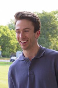 Smiling young man outdoors with teeth visible, suitable for Invisalign or cosmetic dentistry content.