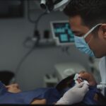 Dentist wearing a mask examines a patient in a dental chair during a treatment appointment.